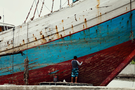 man worker painting old vessel red paint.の写真素材