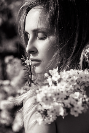 Beautiful happy young woman enjoying smell in a flowering spring garden.の写真素材