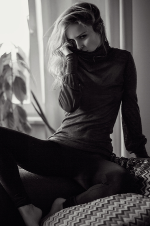 fashion portrait of young blonde elegant woman sitting in sofaの写真素材