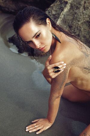 woman on the beach with wet hair and sand on tun skinの写真素材