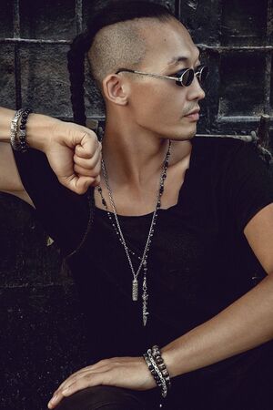 Portrait of an attractive stylish man holding hands to show jewelries, black door background - Imageの写真素材