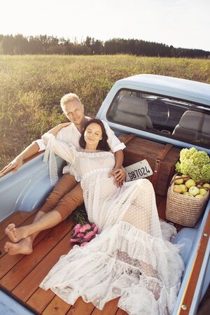 Pregnant woman and her husband happy together and looking each other with love. Outdoor photoshoot in the carの写真素材