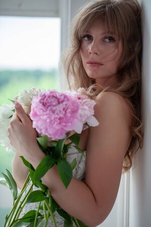 Spring Woman. Beauty Summer model girl. Beautiful Lady with pink peony on her hand. Nature Hairstyle. Natural Makeup.の写真素材