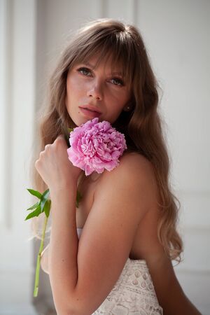 Spring Woman. Beauty Summer model girl. Beautiful Lady with pink peony on her hand. Nature Hairstyle. Natural Makeup.の写真素材