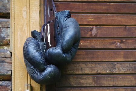 Old black boxing gloves hanging on wooden wallの写真素材