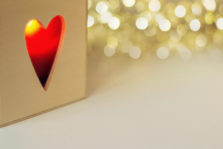 Candle in the wooden box with heart shaped hole on golden bokeh background. Space for textの写真素材