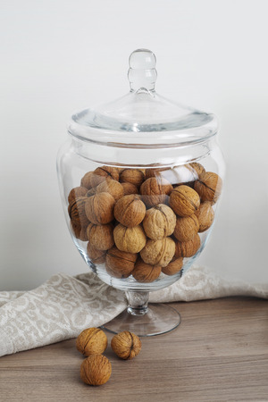 Walnuts in glass bonbonniere, linen napkin on wooden tableの写真素材