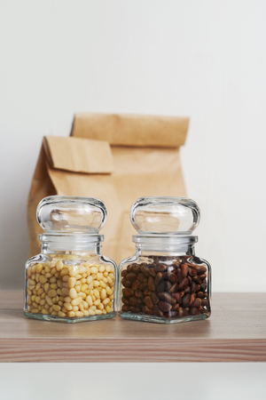 Peeled and unpeeled pine nuts in glass jars on a wooden tableの写真素材
