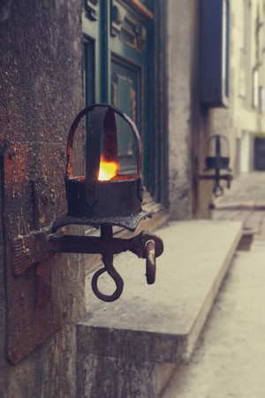 A metal lit lantern with burning fire light placed by two sides around a door. Vintage toned effectの写真素材
