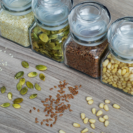Collection of sesame seeds, flax seeds, pumpkin seeds and pine nuts in glass jars