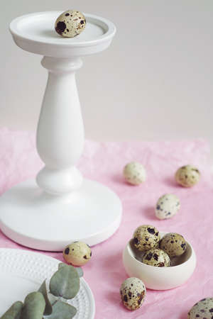 Table setting with white plate, green twig and quail eggs on a pink tissue paper. Prepare to Easter. の写真素材