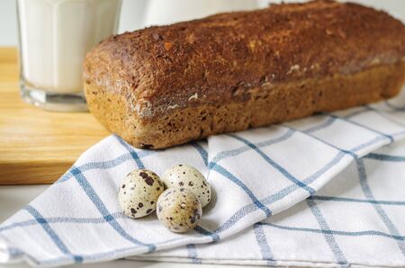 Homemade gluten free bread with linseed flour and psyllium husk. Glass of milk,quail eggs on a...