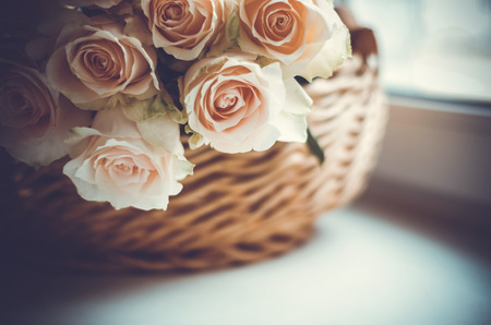 Bouquet of pale pink cream roses in a woven basket on a windowsill. Soft focus. Romance background with copy space.の写真素材