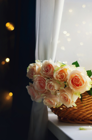 Bouquet of pale pink cream roses in a woven basket on a windowsill. Soft focus. Romance background with copy space.の写真素材