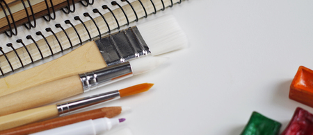 Watercolor paints and notepad on white wooden desk, top view, copy space. Long banner formatの写真素材