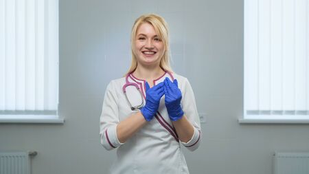 Young women doctor holds toy figures of children in his hands near the heart in hospital or clinic on a white background. Front view. Children protection, love and care concept.の写真素材