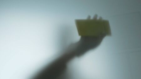 Woman silhouette in gloves cleaning window with rag and cleanser spray at home.の写真素材