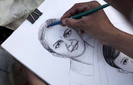 Close-up view of Indian artist drawing pencil portrait of a woman in a public placeのeditorial素材