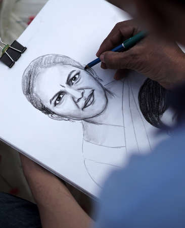 Close-up view of Indian artist drawing pencil portrait of a woman in a public placeのeditorial素材
