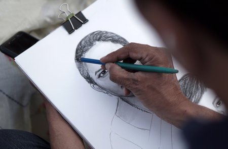 Close-up view of Indian artist drawing pencil portrait of a woman in a public placeのeditorial素材