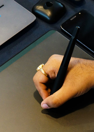 Close-up view of Indian man hand holding pen and sketching on drawing pad