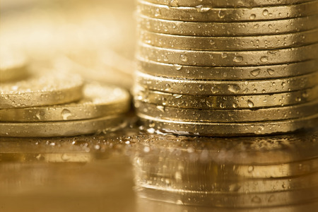 Wet close up gold coins - wealth, money, savings conceptの写真素材