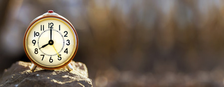 Time concept - red alarm clock standing on a stone - web banner with copy spaceの写真素材