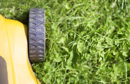 Close-up of a lawn mower wheel on green lawn grass, gardening equipment, web banner, background with copy spaceの写真素材