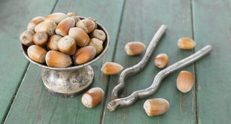 Brown hazelnuts and a vintage nutcracker on a green wooden background, healthy eating, christmas...