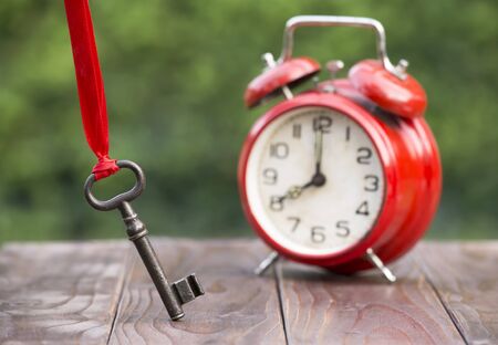 Time management concept, key and classic red alarm clockの写真素材