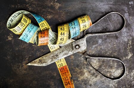 Vintage tape mesaure with blurred scissors on grunge background, diet, loss weight conceptの写真素材