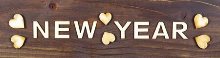 Happy new year letters with hearts on a wooden background, web bannerの写真素材