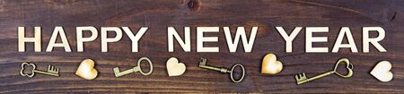 Happy new year letters with hearts and gold keys on wooden background, web bannerの写真素材