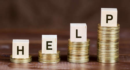 Coronavirus financial stimulus, aid package concept, gold money coins with help word on wooden cubesの写真素材