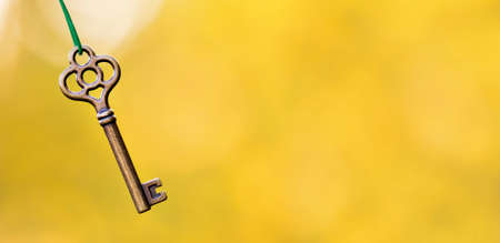 Buying, selling or renting home, real estate, apartment concept, hanging key on gold background. Web banner with copy space.の写真素材