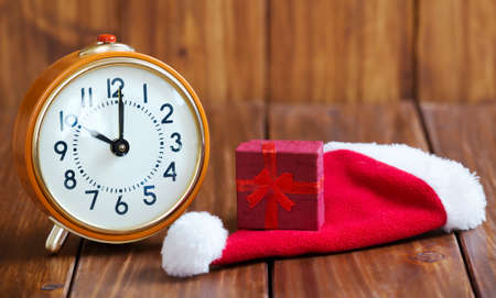 Time to gift, shopping concept, retro alarm clock and red christmas gift box on santa hat