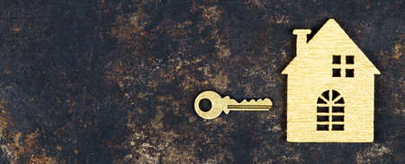 Buy new home, real estate concept, gold key and wooden house shape, web banner with copy spaceの写真素材