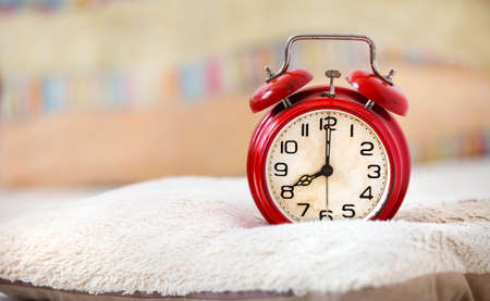 Morning wake up, daylight savings time concept, alarm clock in the bedroom on a pillowの写真素材