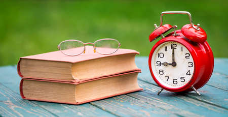 Story book time, storytelling concept, old books and eyeglasses with a classic red alarm clock