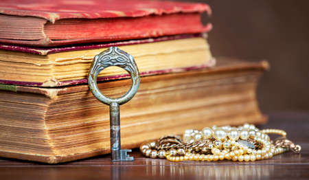 Old vintage rusty key with books and pearl jewelry. Protection, safety, security concept.の写真素材
