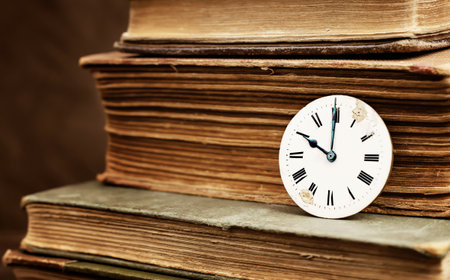 Old books and vintage antique clock face. Story time, storytelling, past background.の写真素材