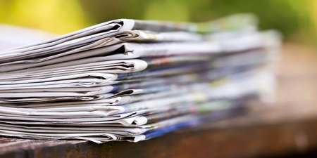 Newspaper stack on a wooden table, daily news bannerの写真素材