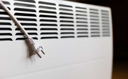 Electrical plug with wire on a heater. Saving electricity, saving power, heating season or energy...