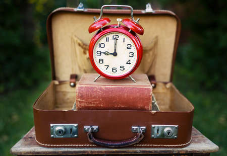 Back to school. Classic bell alarm clock and old books in a vintage retro suitcase, bag.の写真素材