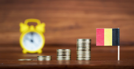 Coins with Belgium flag and alarm clock. Economy, financial or retirement savings and planning background.の写真素材