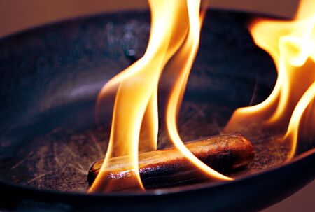 sausage in the flame in frying panの写真素材