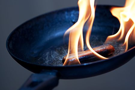 sausage in the flame in frying panの写真素材