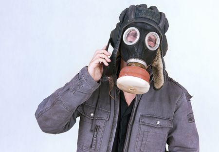 Businessman dress a gas mask, now inconveniently to speak on the phone.の写真素材