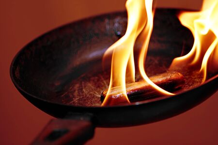 sausage in the flame in frying panの写真素材