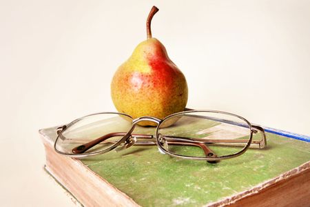 simple still life of pear, very old book and old glassesの写真素材